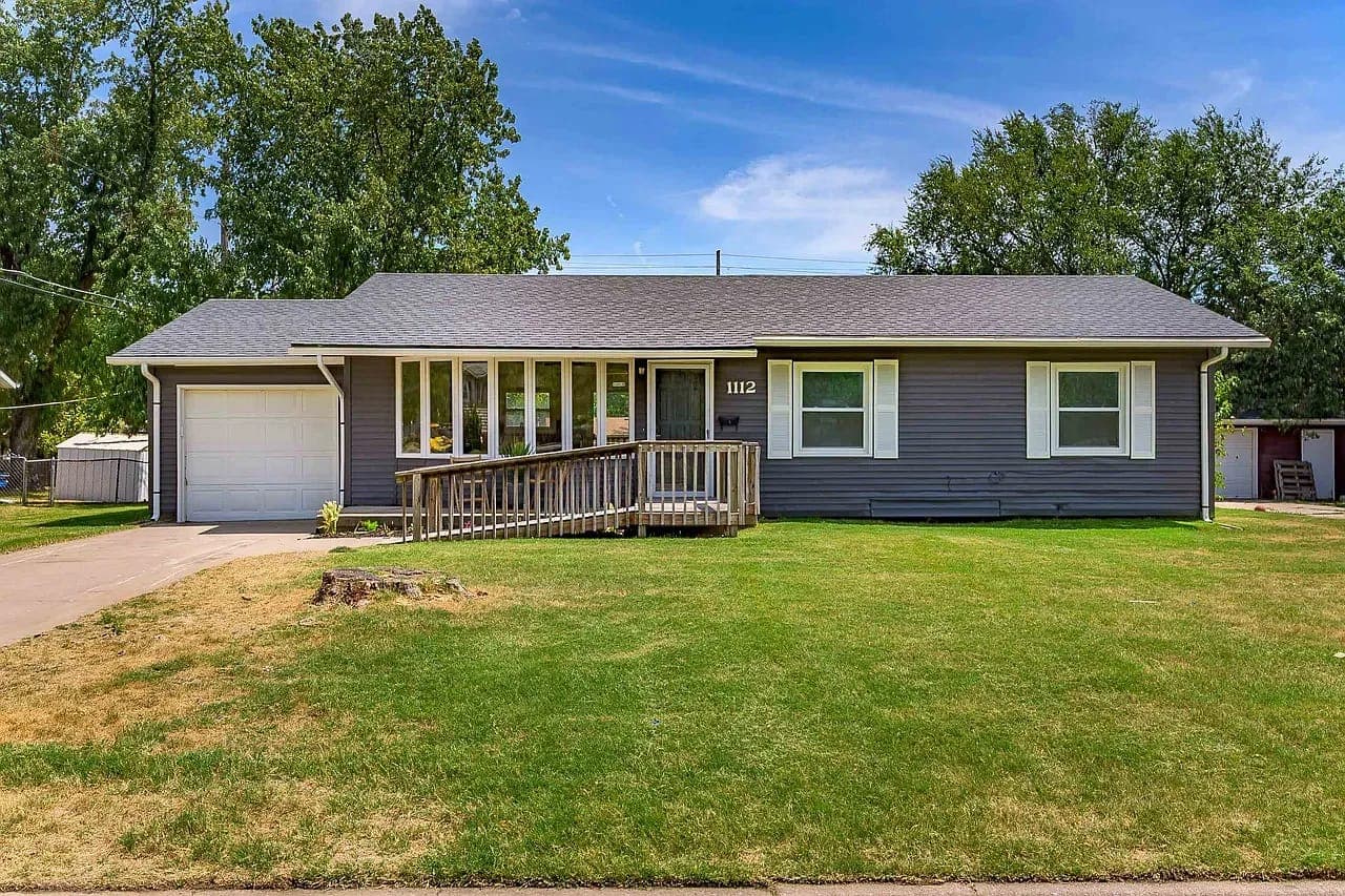 The same ranch house with dark gray siding and new trim, after renovation