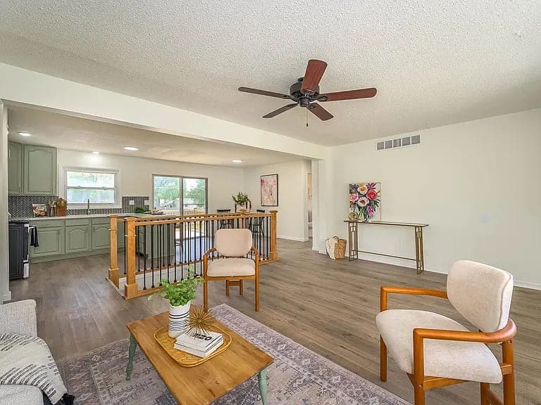 The same living room with new flooring, fresh paint and an open kitchen, after renovation