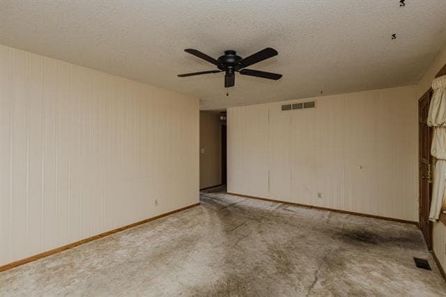 Empty living room with wood paneling and stained carpet, before renovation