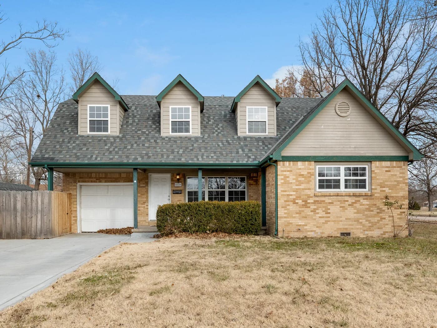 Brick and siding house with three dormers and an attached garage
