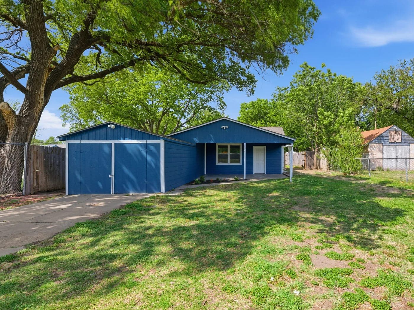 Blue ranch house with a two-car garage and a green lawn